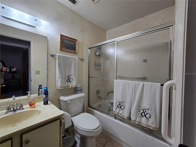 bathroom featuring wallpapered walls, vanity, a textured ceiling, enclosed tub / shower combo, and tile patterned floors