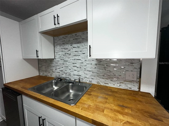 kitchen with butcher block countertops, a sink, dishwasher, and white cabinetry