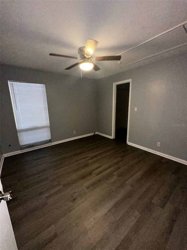 empty room featuring baseboards, ceiling fan, dark wood-style flooring, and a textured ceiling