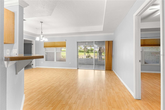 9287 SW 91st Court Rd, Ocala, FL 34481 - unfurnished living room with a chandelier, light wood-style flooring, a tray ceiling, baseboards, and a textured ceiling