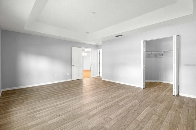 9287 SW 91st Court Rd, Ocala, FL 34481 - unfurnished bedroom featuring light wood-style flooring, baseboards, a tray ceiling, and a closet