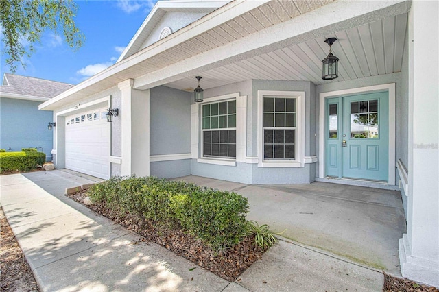 9287 SW 91st Court Rd, Ocala, FL 34481 - view of exterior entry with a garage, covered porch, driveway, and stucco siding