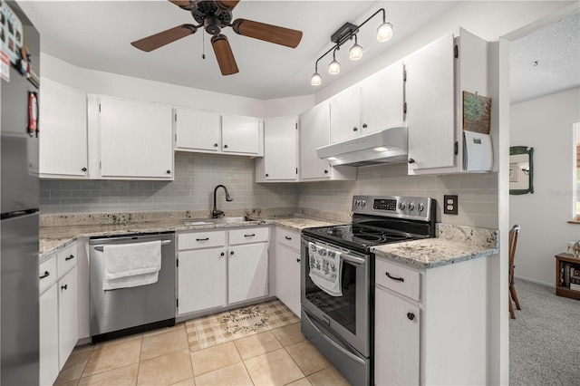 kitchen with appliances with stainless steel finishes, under cabinet range hood, a sink, decorative backsplash, and ceiling fan