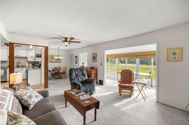 living area featuring a ceiling fan, a chandelier, light carpet, and a textured ceiling