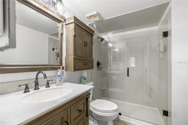 bathroom with toilet, a stall shower, and vanity
