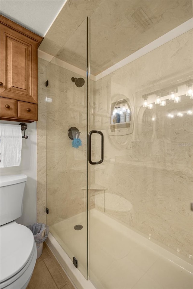 full bath with a stall shower, toilet, and tile patterned floors