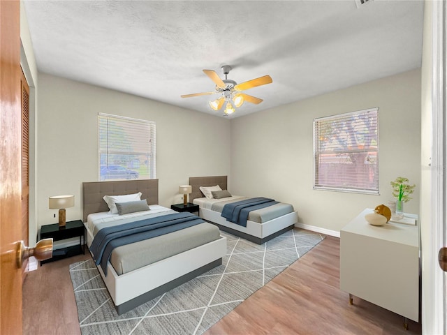 10739 SE 44th Ter, Belleview, FL 34420 - bedroom featuring wood finished floors, multiple windows, baseboards, and a ceiling fan