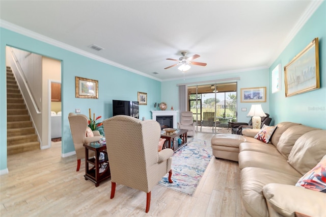 6868 SW 95th Cir, Ocala, FL 34481 - living area featuring stairway, ornamental molding, light wood-style flooring, ceiling fan, and a glass covered fireplace