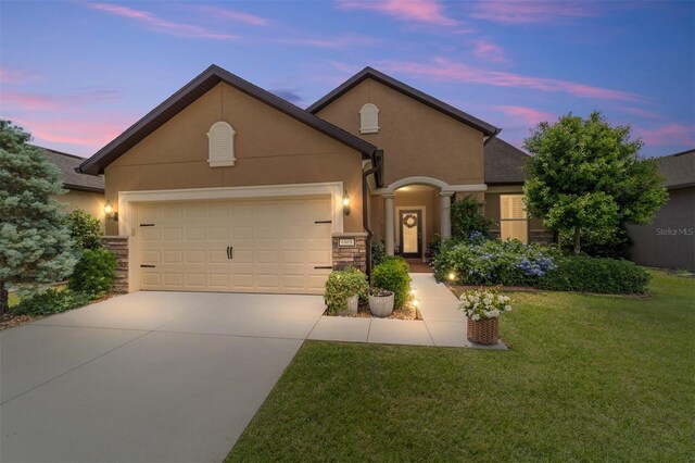6868 SW 95th Cir, Ocala, FL 34481 - view of front facade featuring driveway, an attached garage, a front lawn, stucco siding, and stone siding