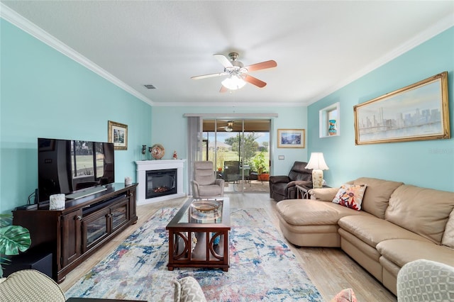 6868 SW 95th Cir, Ocala, FL 34481 - living room featuring ornamental molding, a ceiling fan, wood finished floors, and a glass covered fireplace