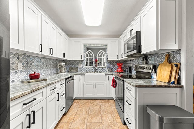 8874 SW 95th St Unit E, Ocala, FL 34481 - kitchen with stainless steel appliances, a sink, white cabinets, and decorative backsplash