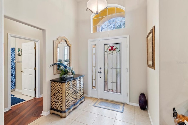foyer entrance with a towering ceiling, baseboards, and tile patterned flooring