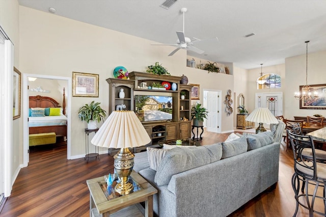 living area with wood finished floors, a ceiling fan, a chandelier, and baseboards