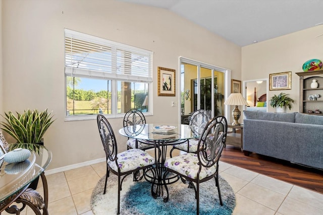 dining area with light tile patterned floors, vaulted ceiling, and baseboards