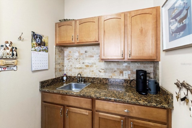 kitchen with a sink, backsplash, and dark stone countertops