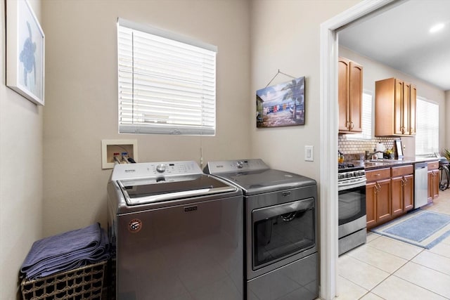 laundry room featuring washing machine and clothes dryer and light tile patterned floors