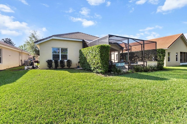 back of property featuring a tile roof, stucco siding, a lawn, glass enclosure, and central AC