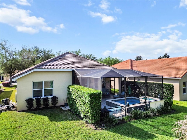 rear view of house with stucco siding, a tile roof, a yard, a pool with connected hot tub, and glass enclosure
