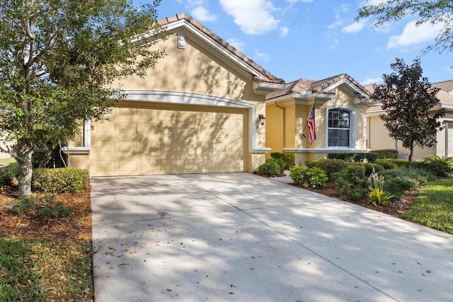 view of front of home with stucco siding, concrete driveway, a garage, and a tile roof