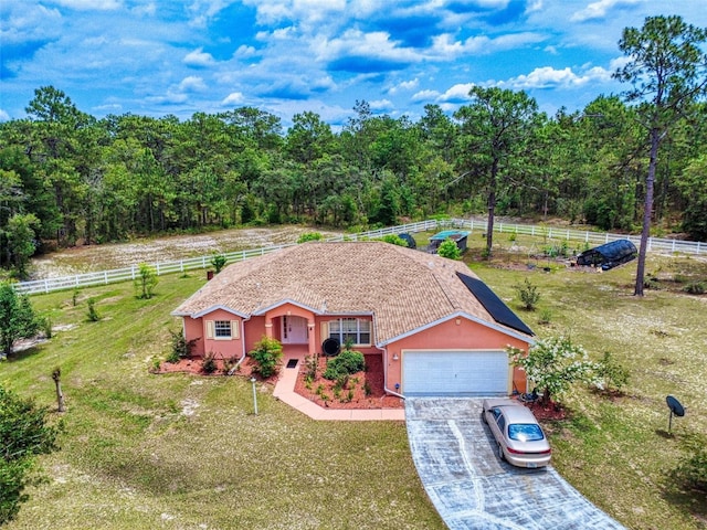 9325 SW 125th Court Rd, Dunnellon, FL 34432 - ranch-style house featuring a garage, driveway, stucco siding, a wooded view, and a view of countryside