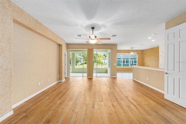 6651 SW 93rd Ct, Ocala, FL 34481 - unfurnished living room featuring light wood finished floors, a ceiling fan, baseboards, a textured wall, and a textured ceiling