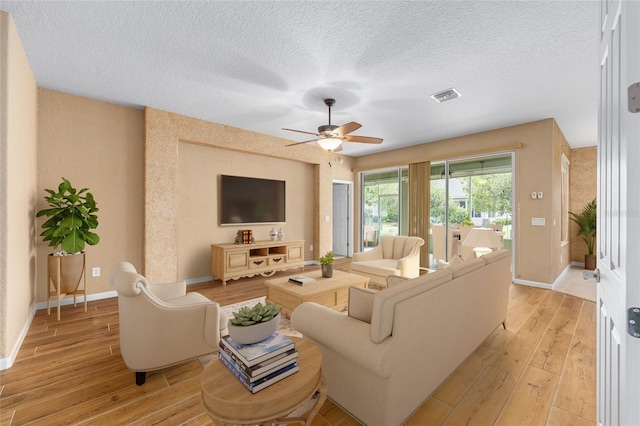6651 SW 93rd Ct, Ocala, FL 34481 - living room featuring light wood-type flooring, baseboards, ceiling fan, and a textured ceiling