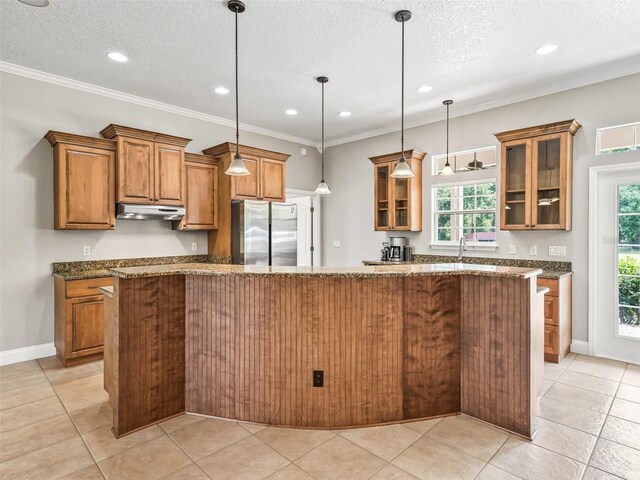 2540 NE 120th St, Anthony, FL 32617 - kitchen with freestanding refrigerator, brown cabinetry, a textured ceiling, under cabinet range hood, and healthy amount of natural light