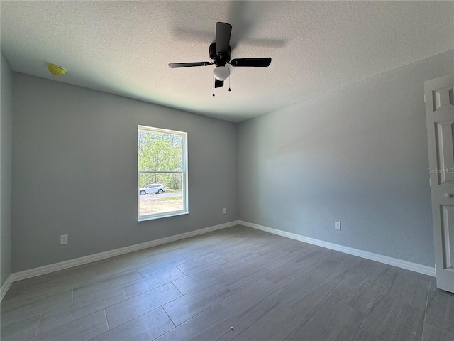 unfurnished room with ceiling fan, dark wood-style floors, baseboards, a textured ceiling, and a smoke detector