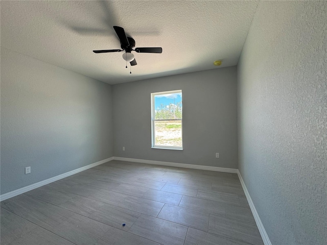 spare room with a ceiling fan, baseboards, a textured ceiling, and a textured wall