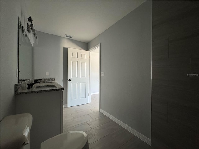 bathroom featuring toilet, baseboards, and vanity