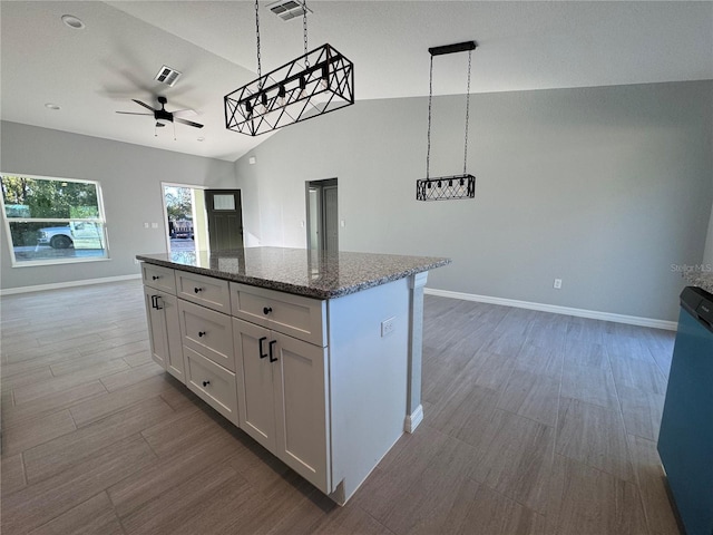 kitchen with open floor plan, a ceiling fan, a kitchen island, wood finished floors, and lofted ceiling