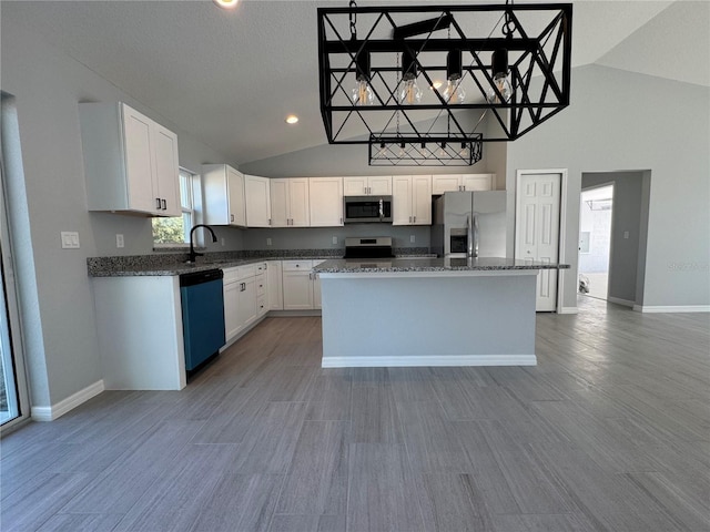 kitchen featuring appliances with stainless steel finishes, a sink, white cabinets, a kitchen island, and baseboards