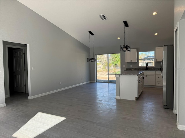 kitchen with freestanding refrigerator, white cabinetry, open floor plan, decorative light fixtures, and baseboards