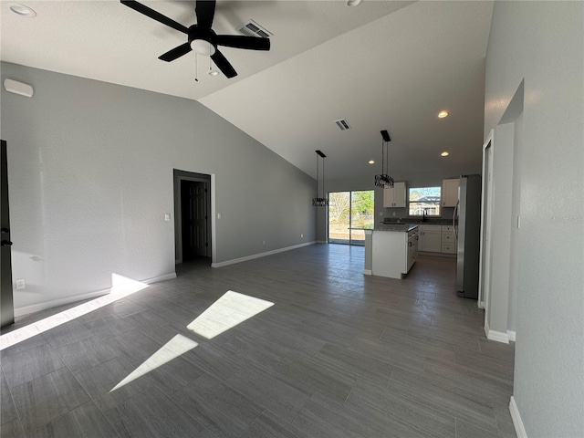 unfurnished living room with ceiling fan, lofted ceiling, and baseboards