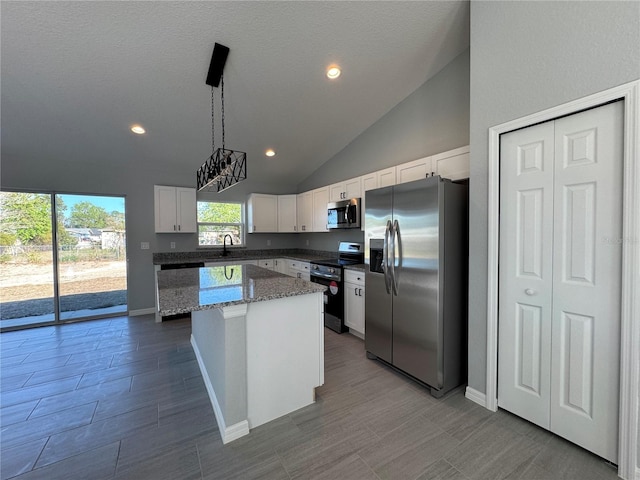 kitchen featuring appliances with stainless steel finishes, a sink, a center island, lofted ceiling, and white cabinets