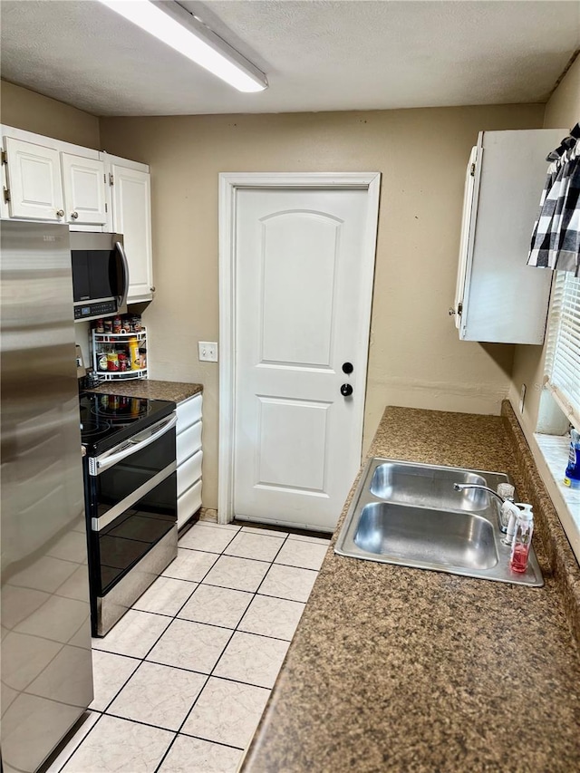 5549 NW 64th St, Ocala, FL 34482 - kitchen with stainless steel appliances, a sink, white cabinets, light tile patterned floors, and dark countertops