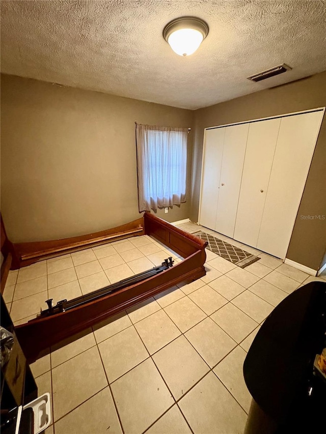 5549 NW 64th St, Ocala, FL 34482 - unfurnished bedroom with a textured ceiling, baseboards, a closet, and tile patterned flooring
