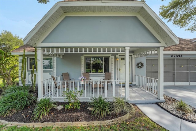 view of front of property with a porch, driveway, a garage, stucco siding, and a shingled roof