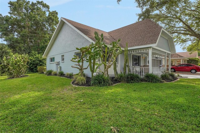 view of property exterior featuring a porch, a shingled roof, and a lawn