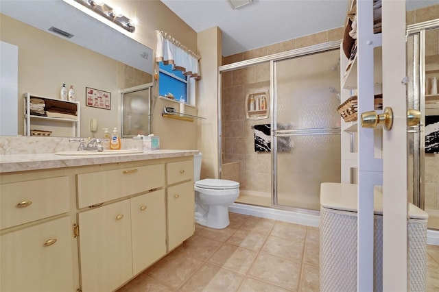 bathroom featuring a stall shower, toilet, vanity, and tile patterned flooring