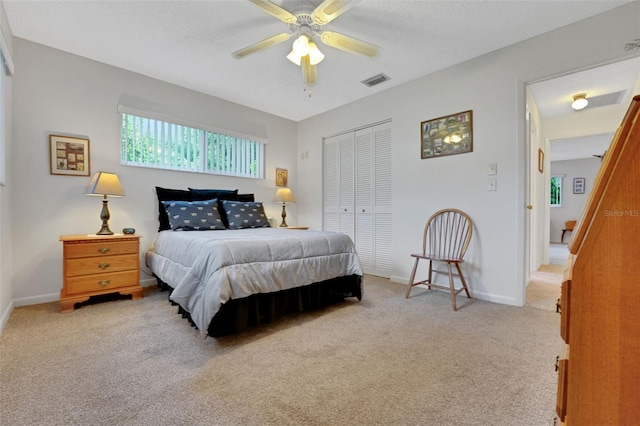 bedroom with light colored carpet, a closet, baseboards, and ceiling fan