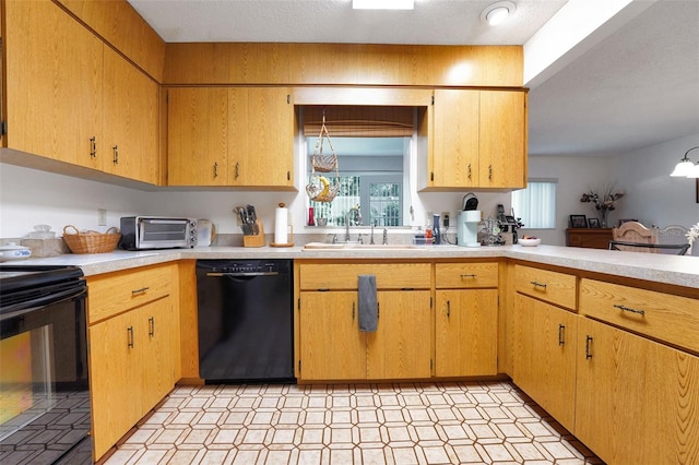 kitchen with black appliances, a sink, light countertops, and light flooring