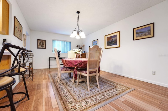 dining area featuring a chandelier, light wood-style floors, and baseboards