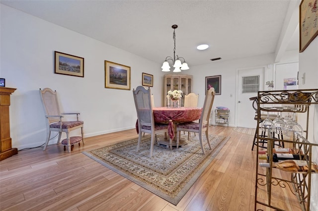 dining room featuring a chandelier, light wood-type flooring, and baseboards