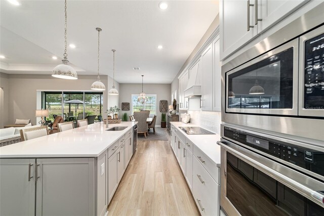 8606 SW 61st Loop, Ocala, FL 34481 - kitchen with appliances with stainless steel finishes, a sink, a kitchen island with sink, light wood-type flooring, and light countertops