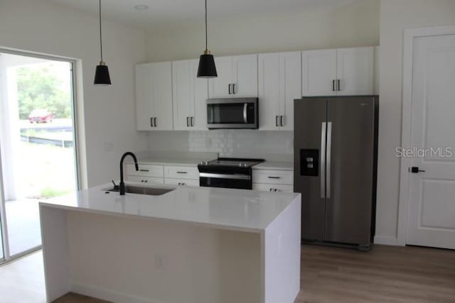 kitchen featuring stainless steel appliances, a sink, white cabinets, and light wood-type flooring