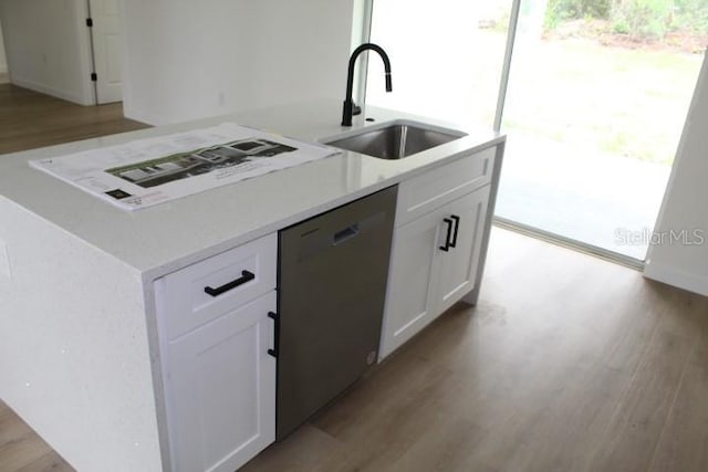 kitchen featuring dishwasher, a sink, an island with sink, light wood-style floors, and white cabinetry