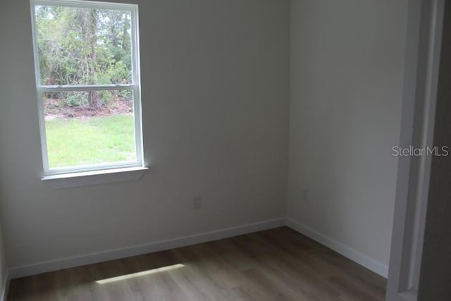 unfurnished room with baseboards, healthy amount of natural light, and wood finished floors