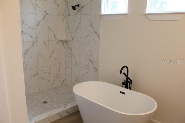 bathroom with a tile shower and a freestanding bath