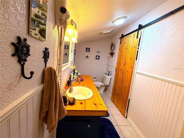 7023 W Riverbend Rd, Dunnellon, FL 34433 - bathroom featuring tile patterned floors, a textured ceiling, wainscoting, toilet, and vanity